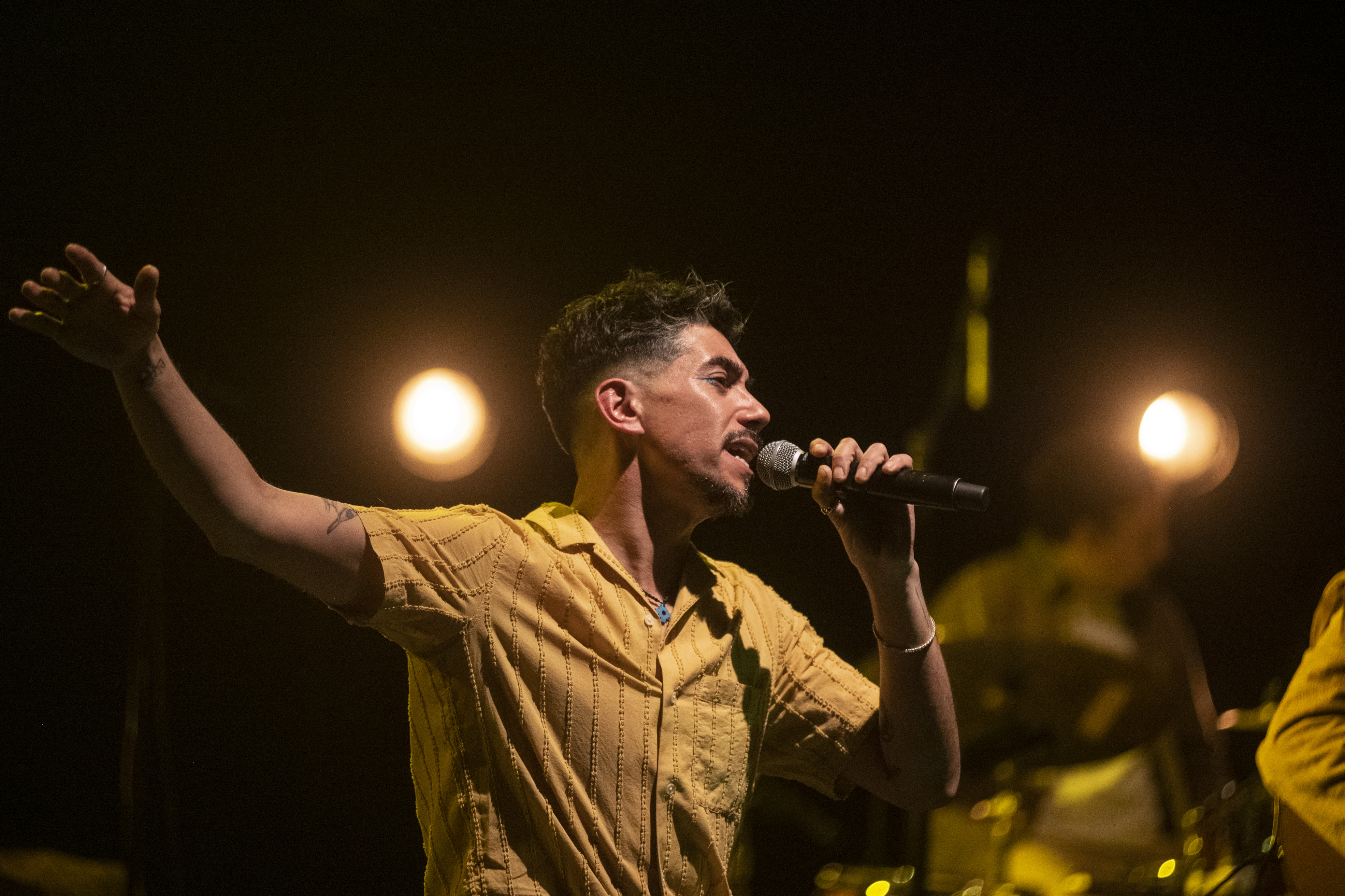 Duberly cantando en escena con camisa amarilla.