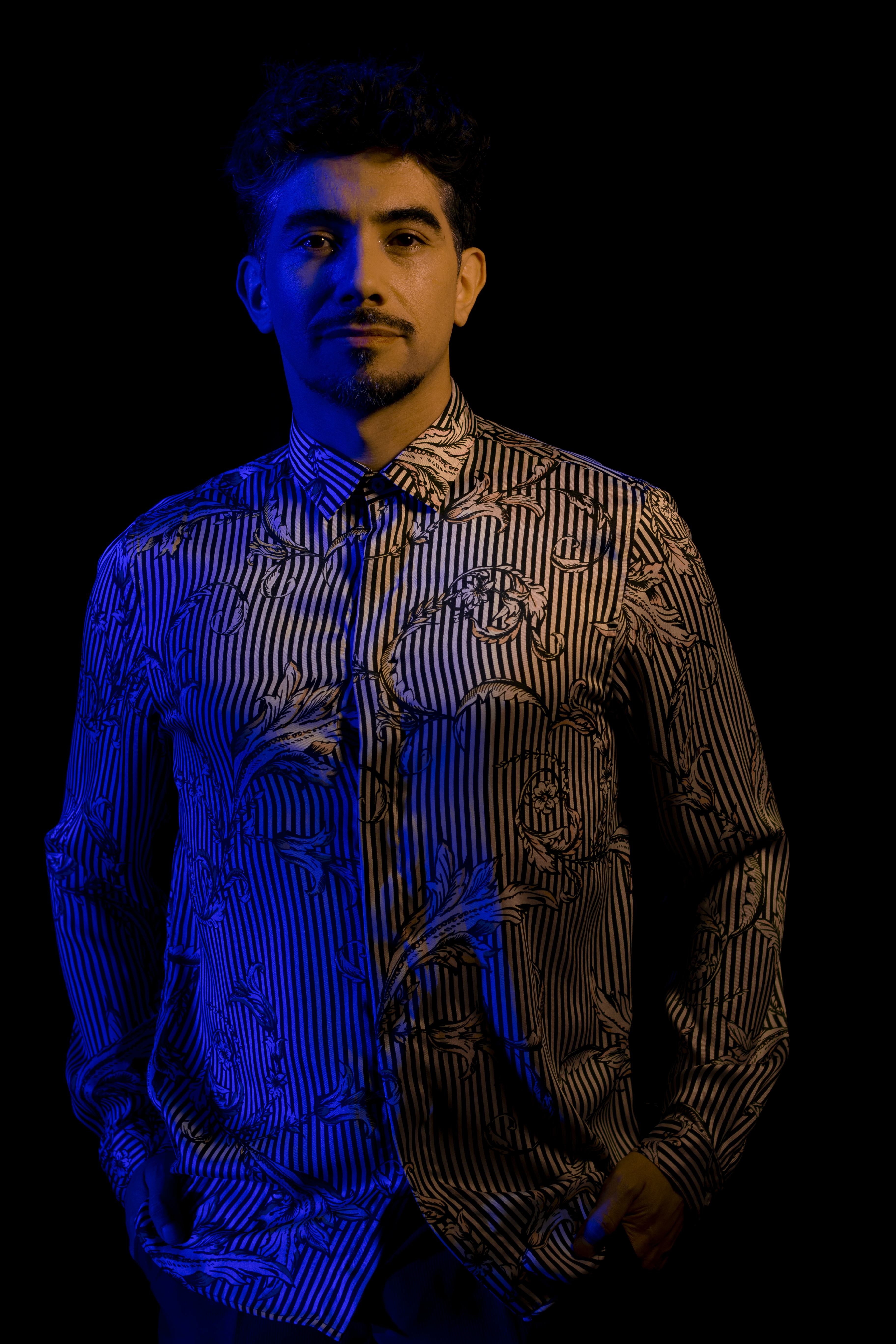 Retrato de Duberly con camisa rayada bajo una iluminación azul.